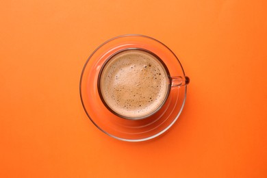 Photo of Fresh coffee in cup on orange background, top view