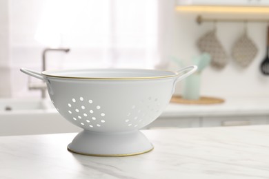 Photo of Clean colander on white marble table in kitchen. Space for text