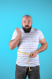 Fat man with measuring tape on color background. Weight loss