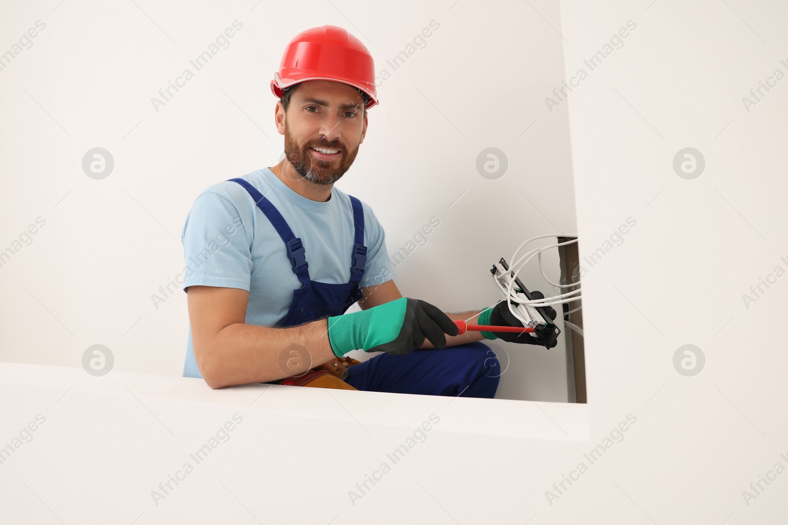 Photo of Electrician with screwdriver fixing patch panel indoors