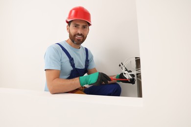 Electrician with screwdriver fixing patch panel indoors