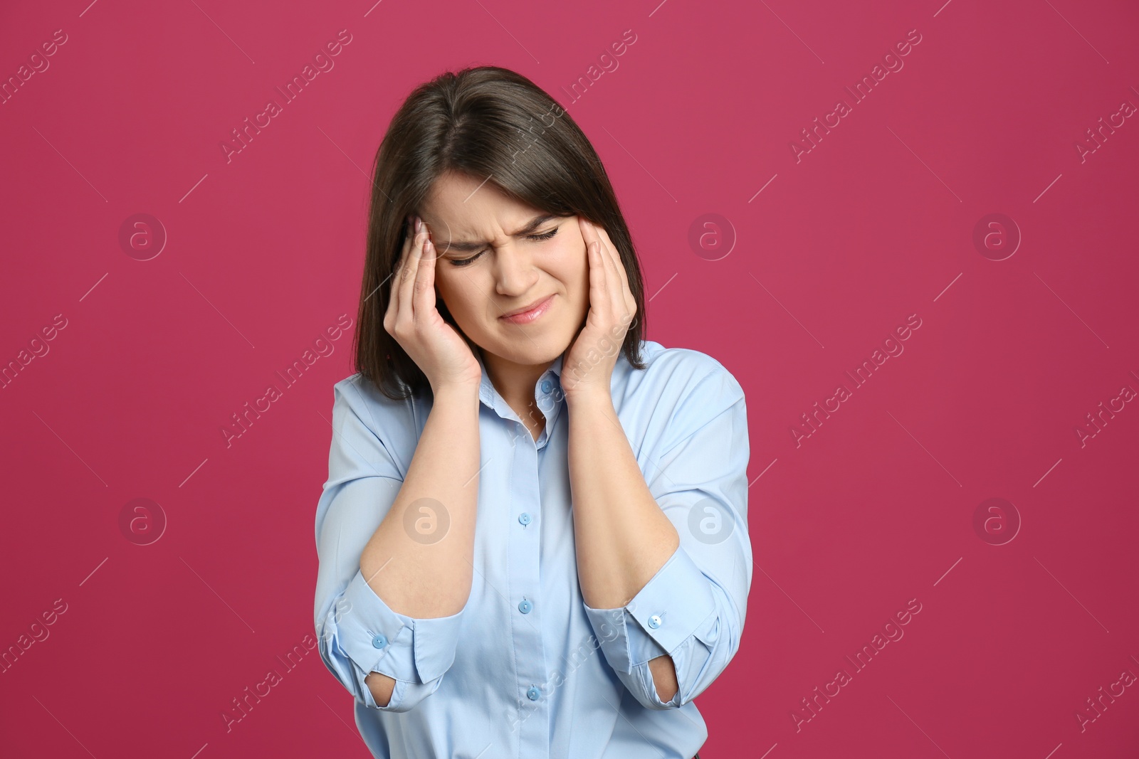 Photo of Young woman suffering from migraine on crimson background