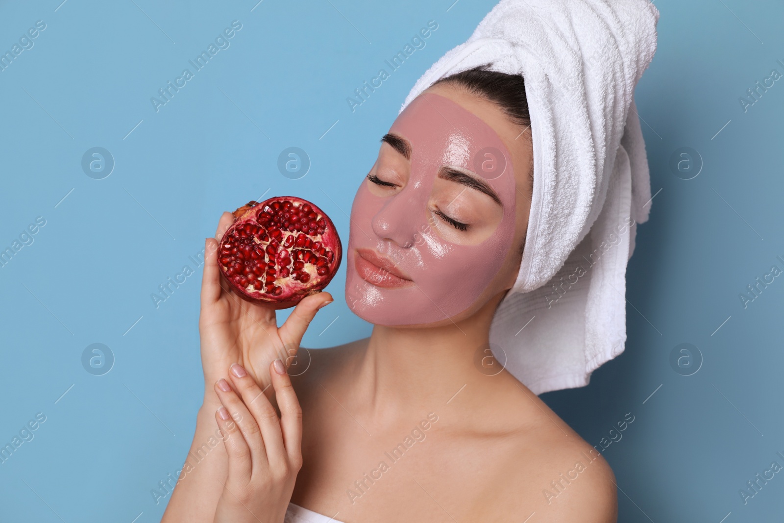 Photo of Woman with pomegranate face mask and fresh fruit on light blue background