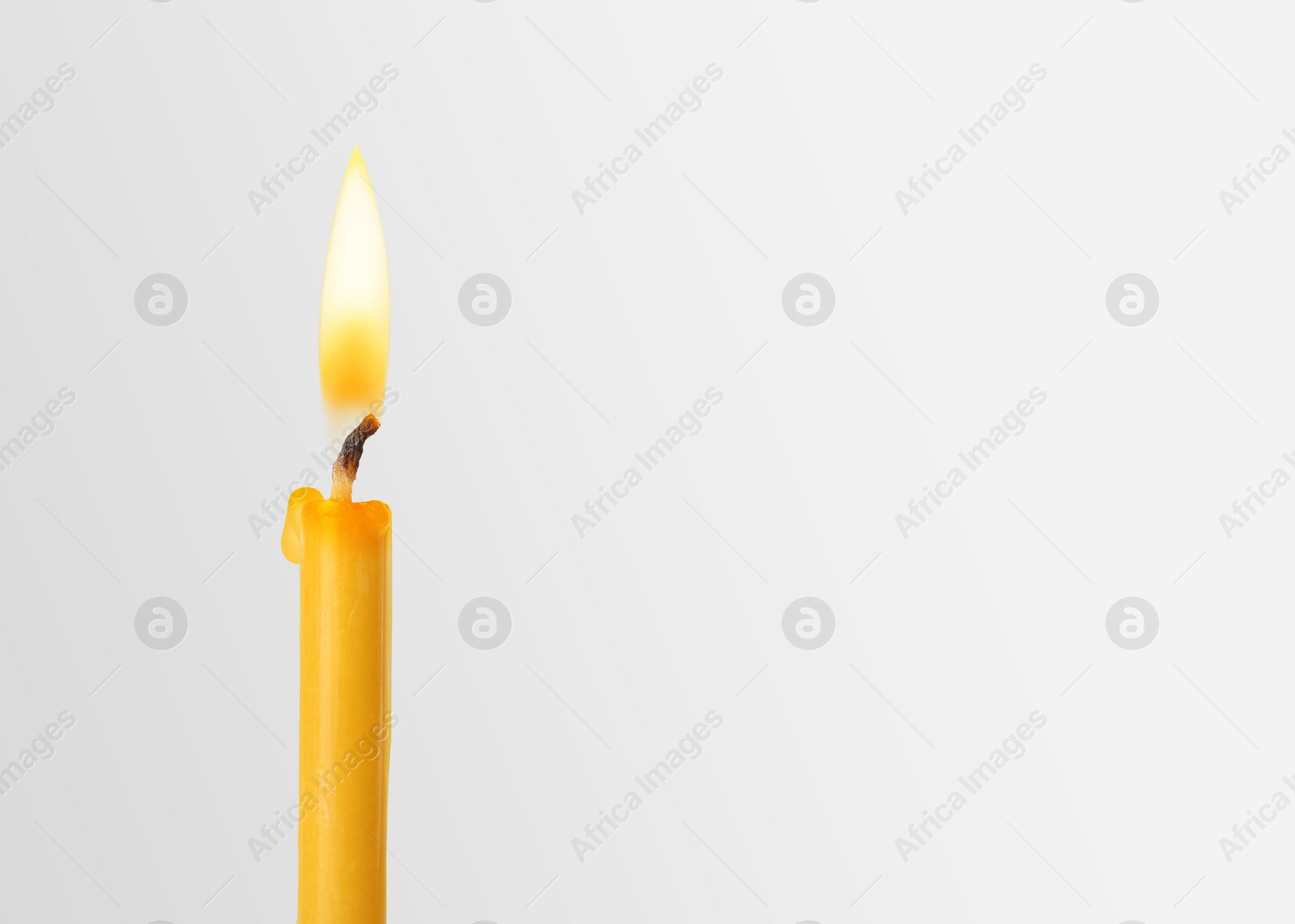 Image of Burning church candle on light background. Space for text