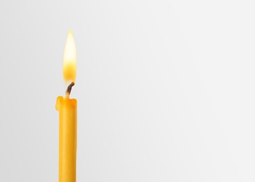 Image of Burning church candle on light background. Space for text