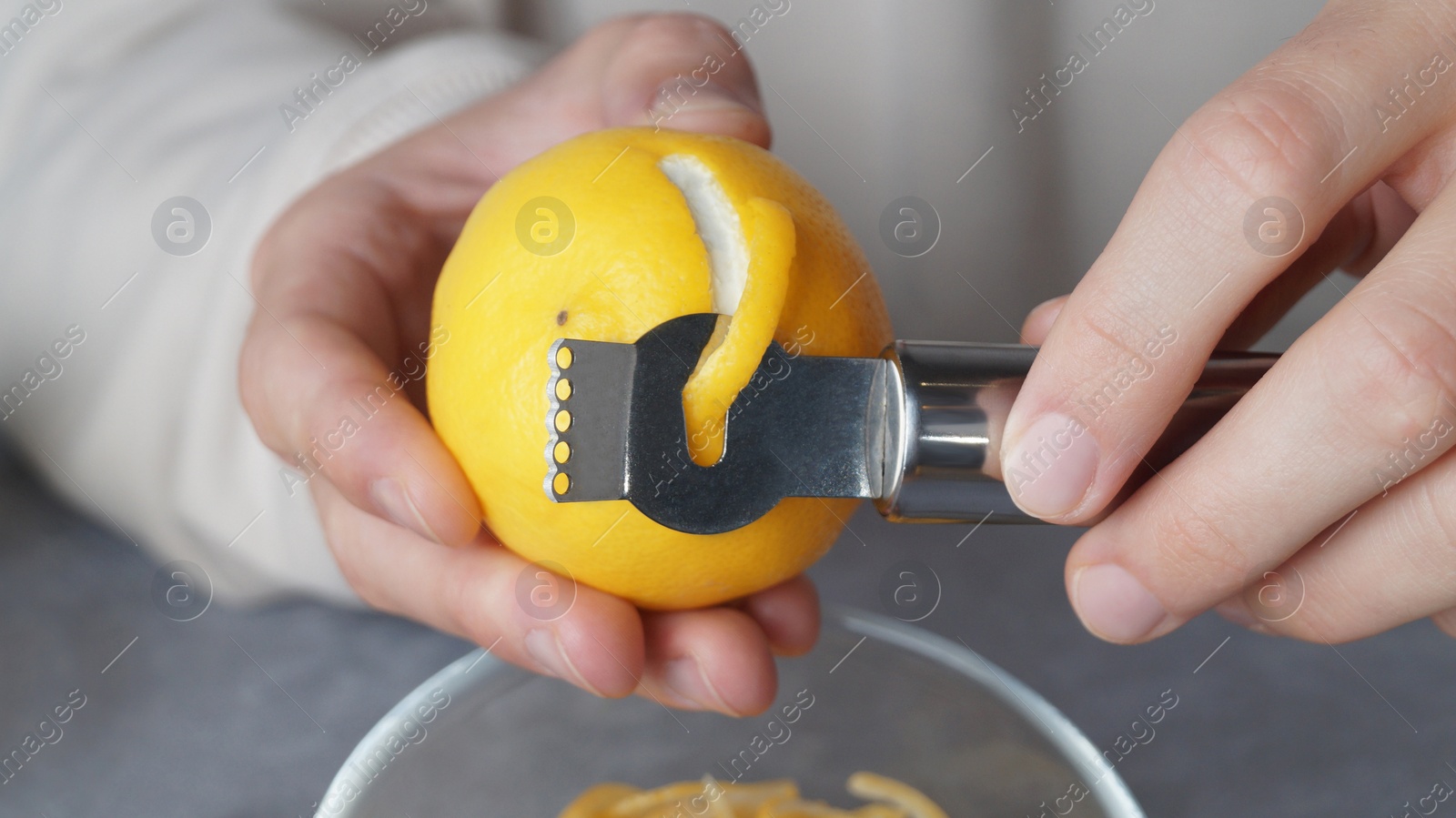 Photo of Man peeling fresh lemon with zester, closeup view