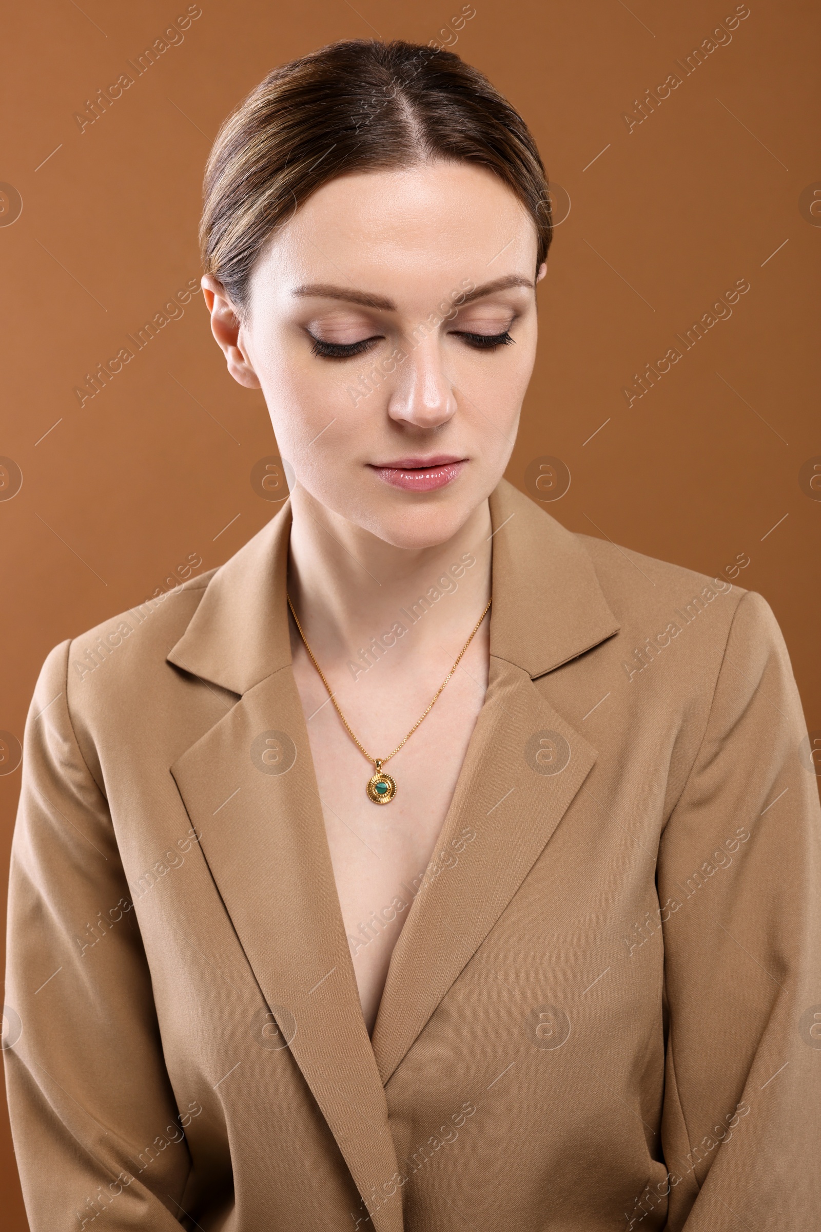 Photo of Beautiful woman with elegant necklace on brown background