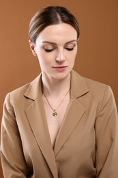 Photo of Beautiful woman with elegant necklace on brown background