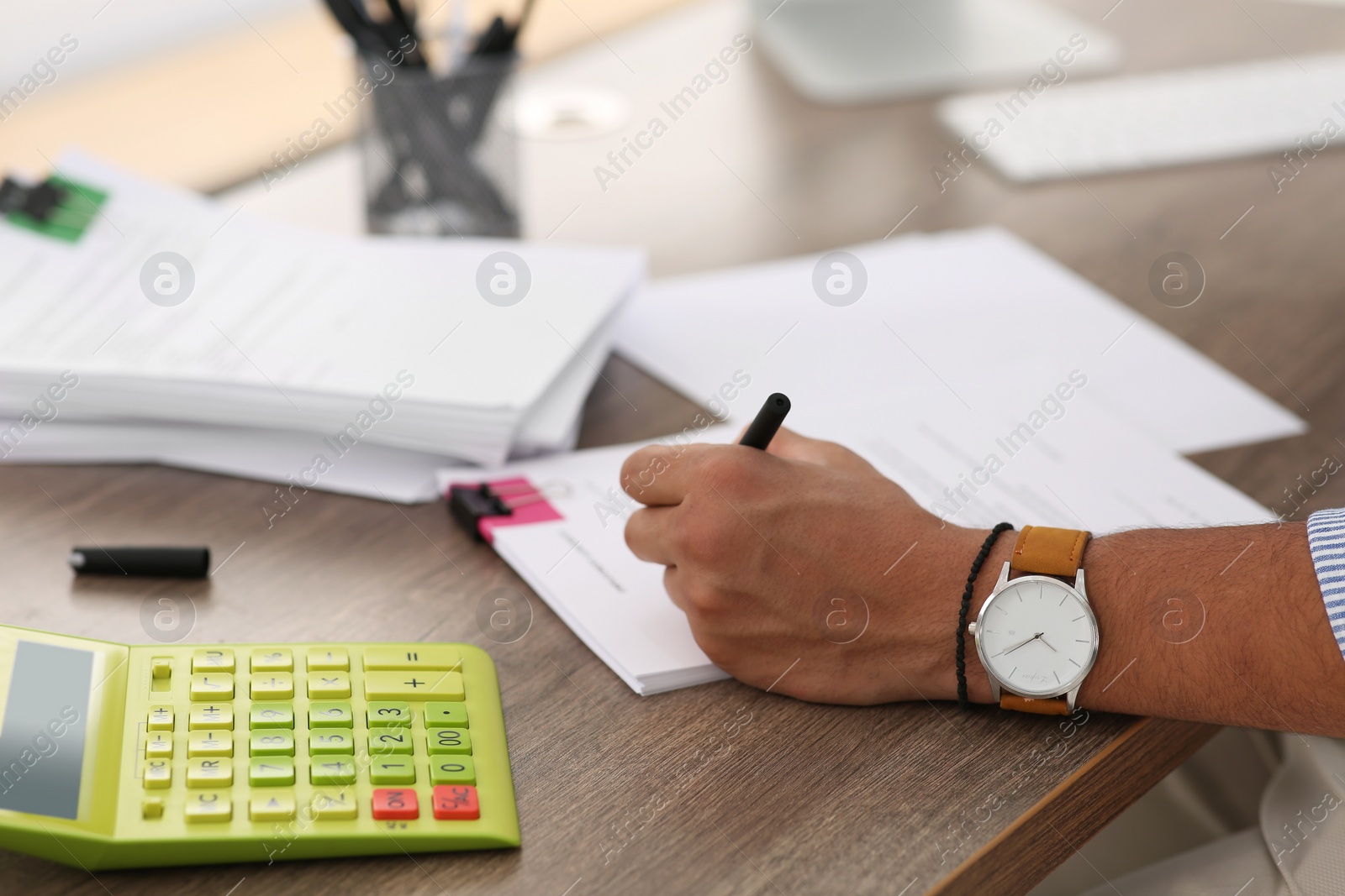 Photo of Man working with documents at wooden table in office, closeup