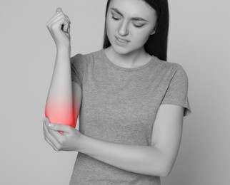 Image of Woman suffering from pain in elbow. Black and white effect