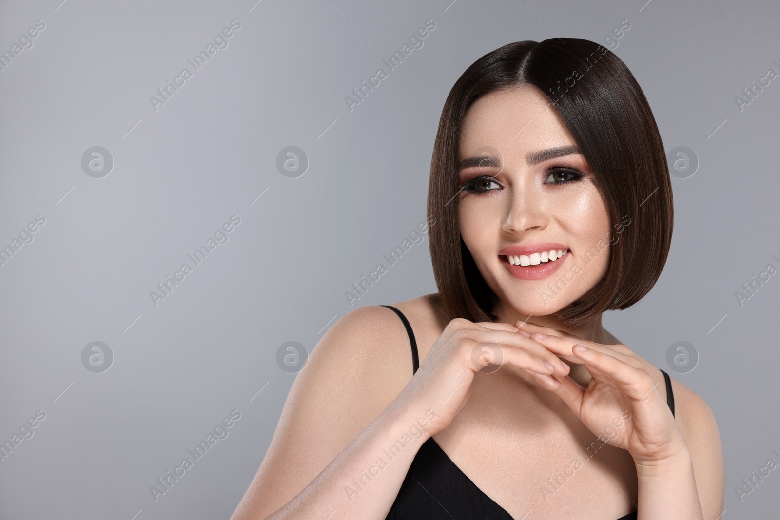 Image of Portrait of pretty young woman with brown hair smiling on grey background, space for text