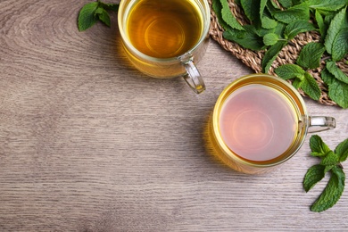 Photo of Fresh green tea with mint on wooden table, flat lay. Space for text