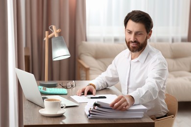 Photo of Happy businessman working with documents at wooden table in office