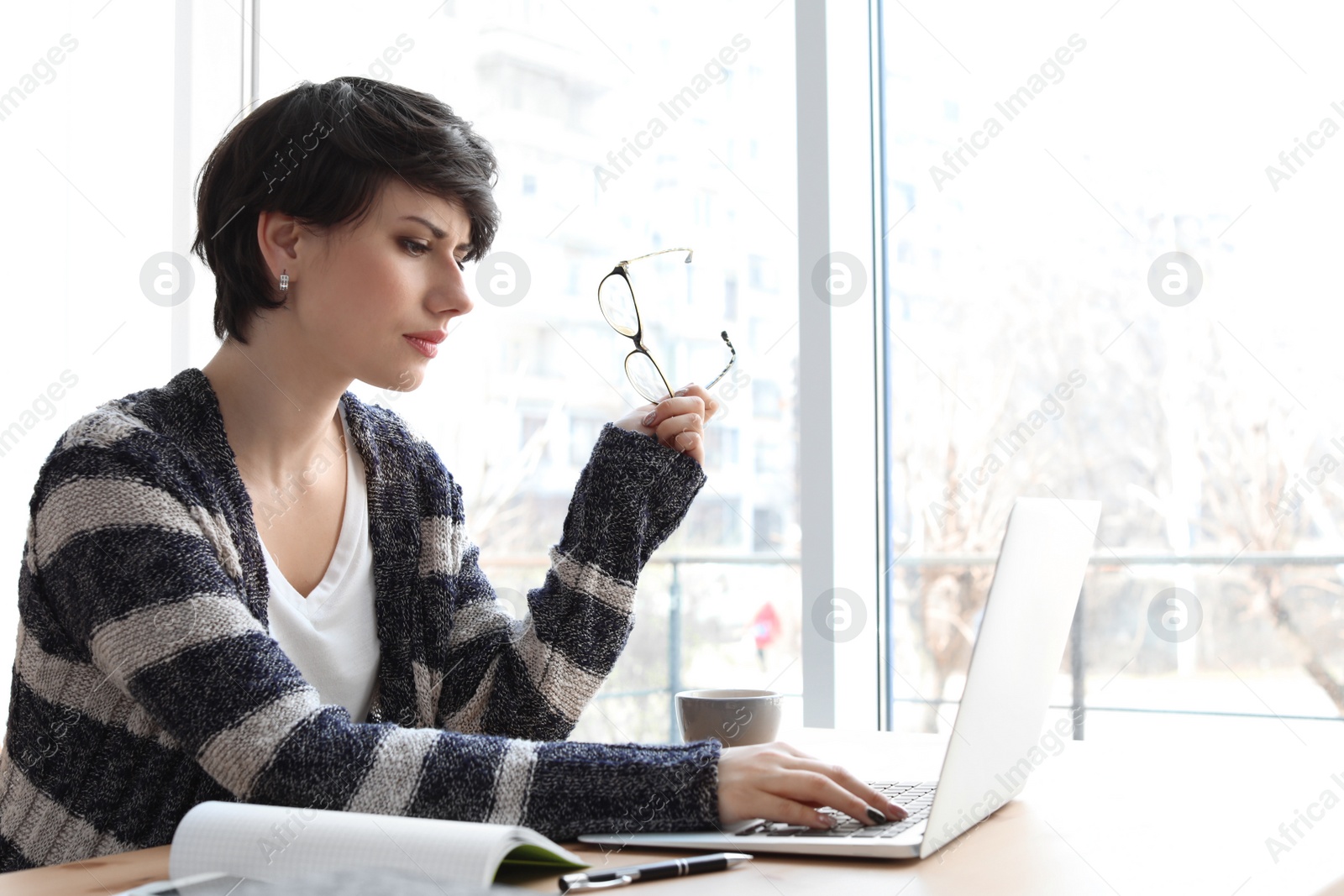 Photo of Young woman working with laptop at desk. Home office