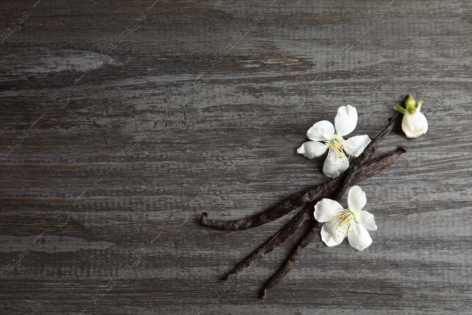 Photo of Flat lay composition with aromatic vanilla sticks and flowers on wooden background, space for text