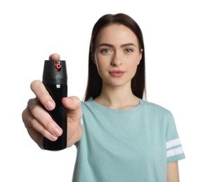 Young woman using pepper spray on white background