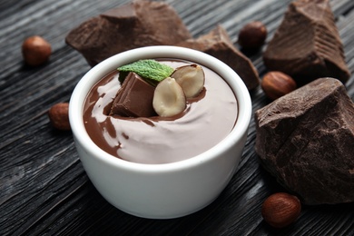 Ceramic bowl with sweet chocolate cream and chunks on wooden table