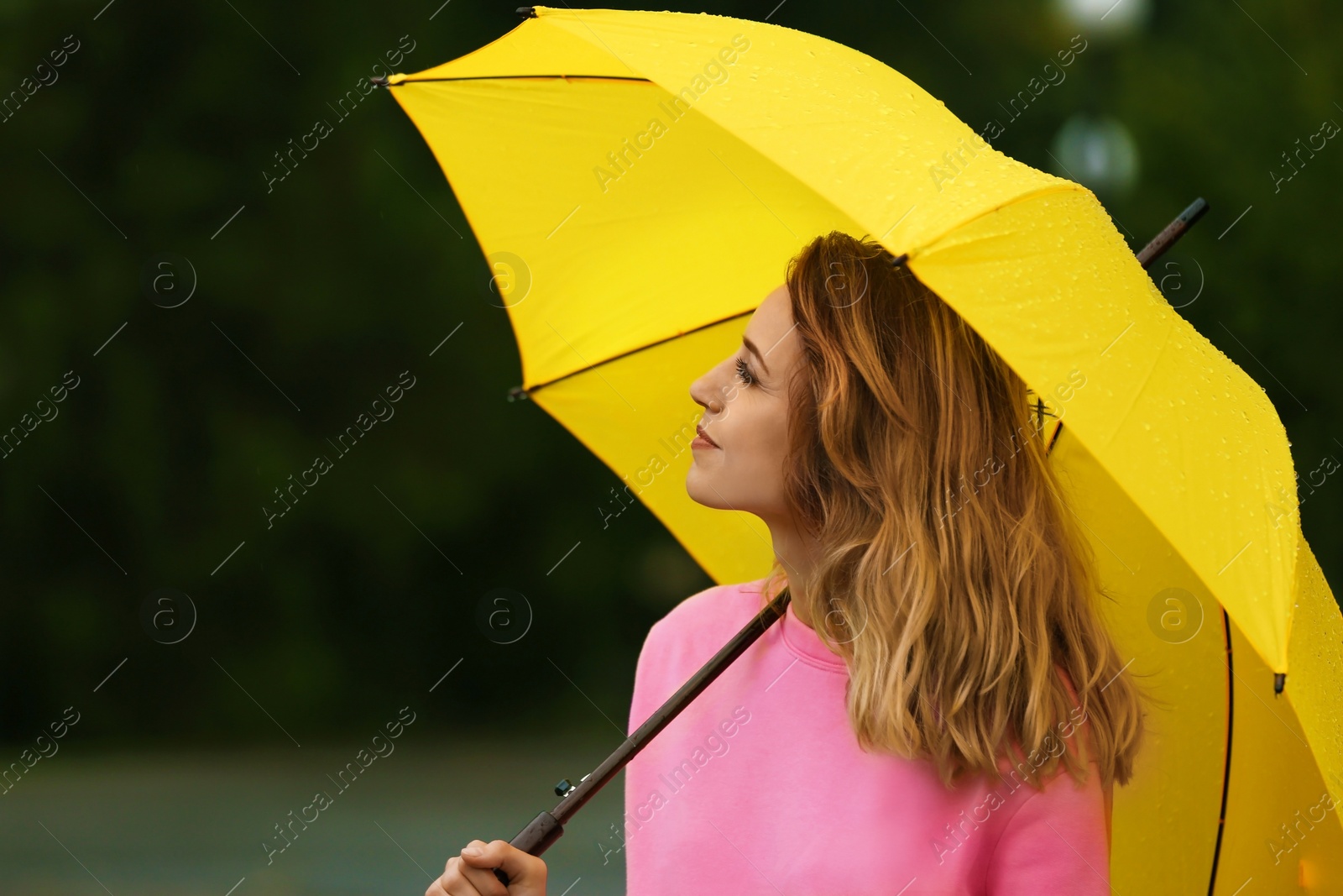 Photo of Happy young woman with bright umbrella under rain outdoors