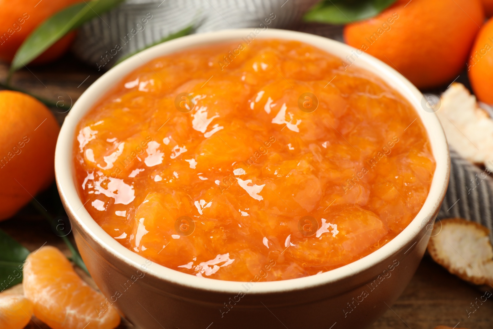 Photo of Tasty tangerine jam in bowl on wooden table, closeup