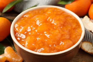 Photo of Tasty tangerine jam in bowl on wooden table, closeup