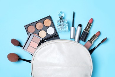 Photo of Cosmetic bag and makeup products with accessories on light blue background, flat lay