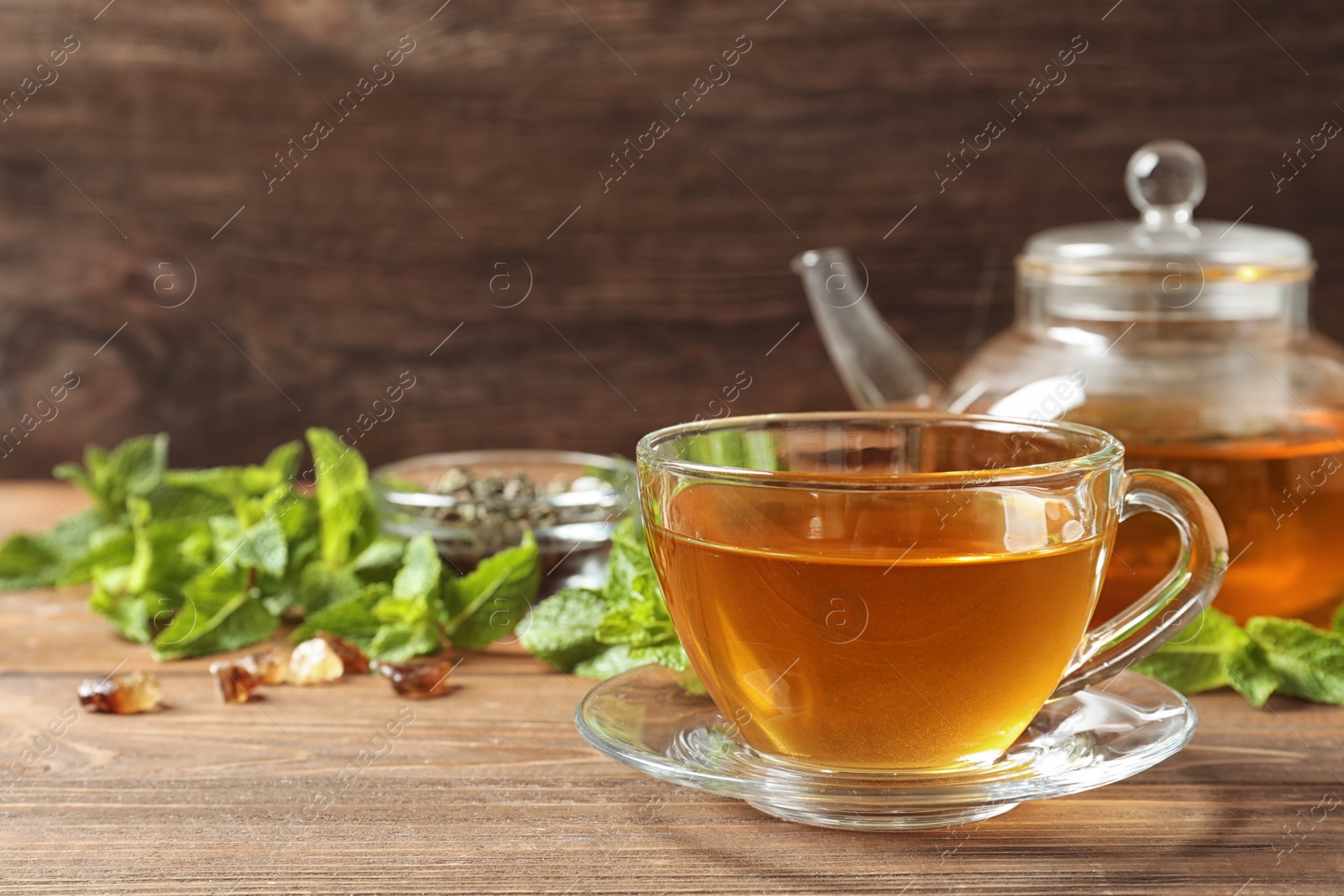 Photo of Cup with hot aromatic mint tea on wooden table