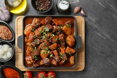 Delicious beef stew and ingredients on grey table, flat lay. Space for text