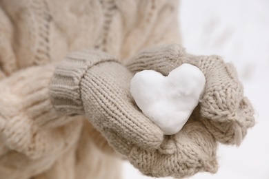 Photo of Woman holding heart made of snow, closeup view