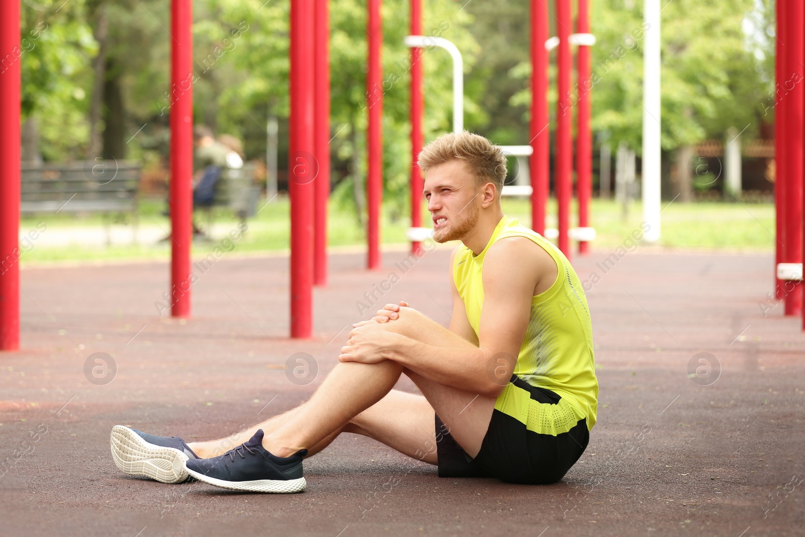 Photo of Young man suffering from knee pain on sports ground