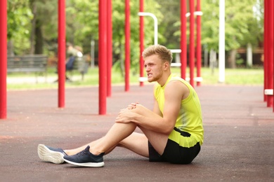 Photo of Young man suffering from knee pain on sports ground