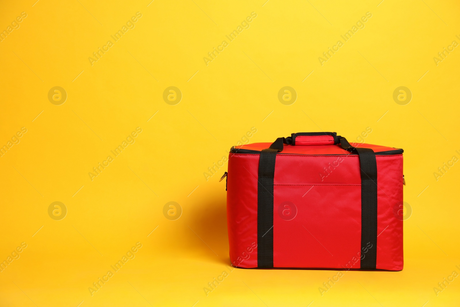Photo of Modern red thermo bag on yellow background. Space for text