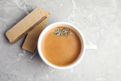 Photo of Delicious wafers and cup of coffee for breakfast on grey marble table, flat lay
