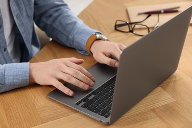 Photo of Man working on laptop at wooden desk, closeup
