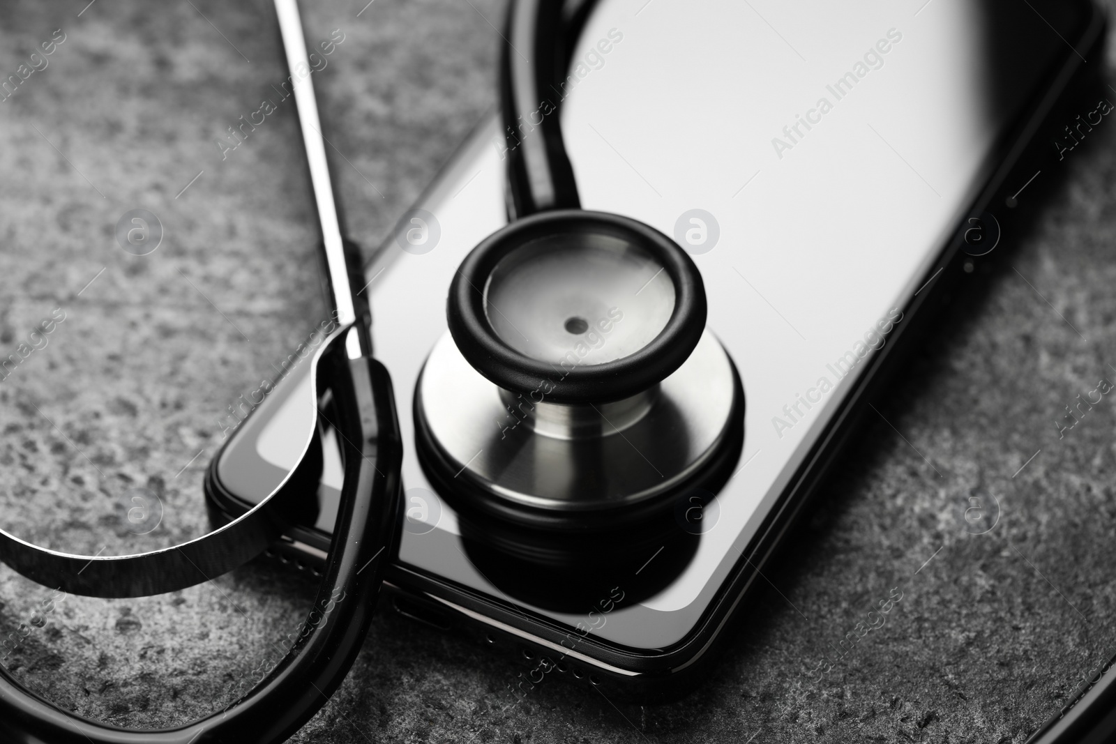 Photo of Modern smartphone and stethoscope on grey table, closeup