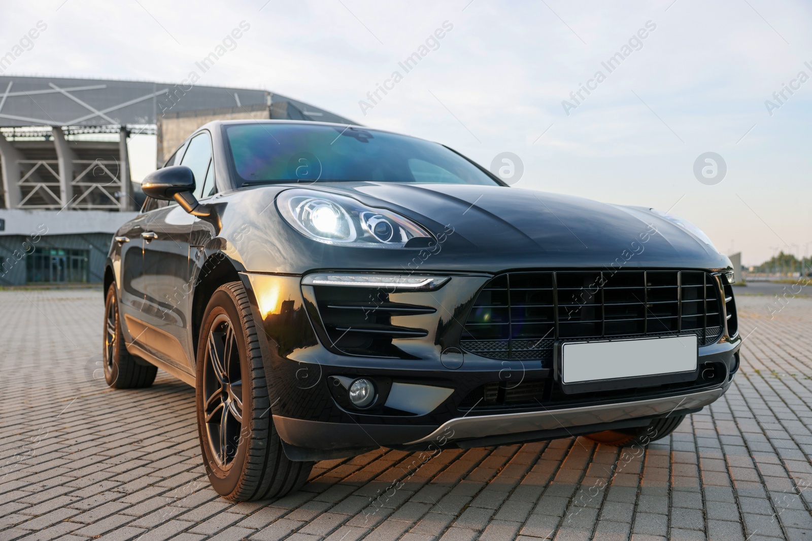 Photo of Modern black car parked on stone pavement outdoors