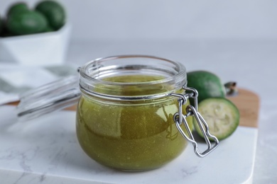 Photo of Feijoa jam in glass jar on white marble board, closeup