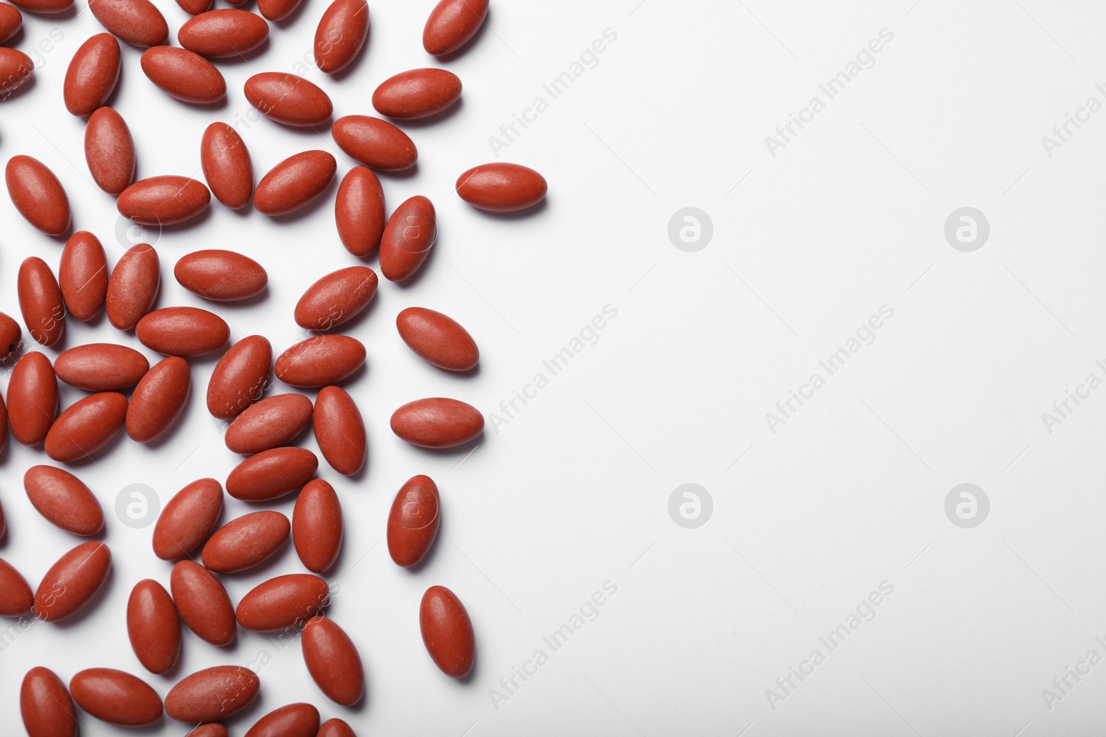 Photo of Red pills on white background, flat lay with space for text. Anemia treatment