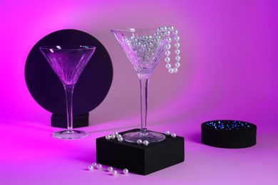 Beautiful composition with martini glasses and pearls on pink background