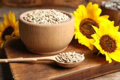 Photo of Raw peeled sunflower seeds and flowers on wooden board