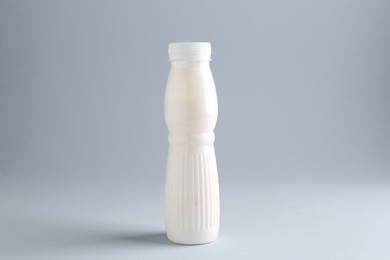 Photo of Tasty yogurt in bottle on light grey background