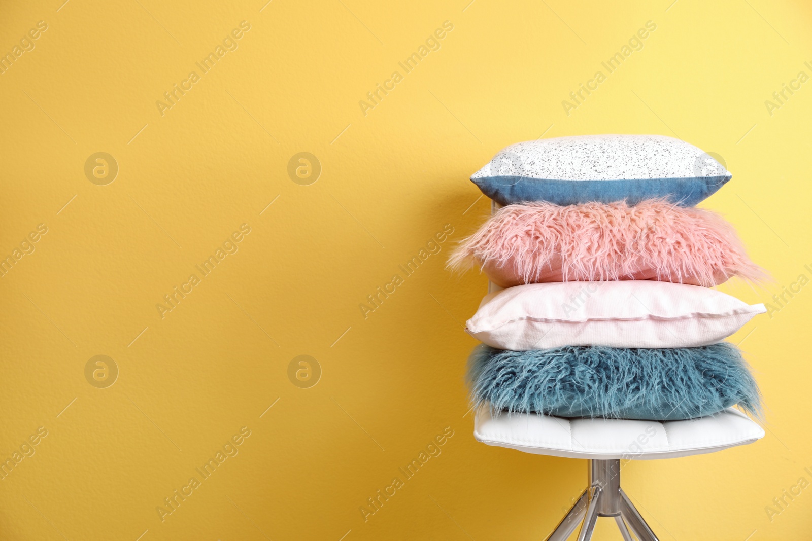 Photo of Chair with many different pillows and space for text on color background