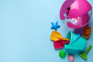 Photo of Beach ball and sand toys on light blue background, space for text