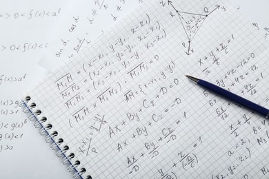 Photo of Notebook with different mathematical formulas and pen, top view