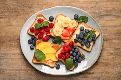 Photo of Tasty toasts with different spreads and fruits on wooden table, top view