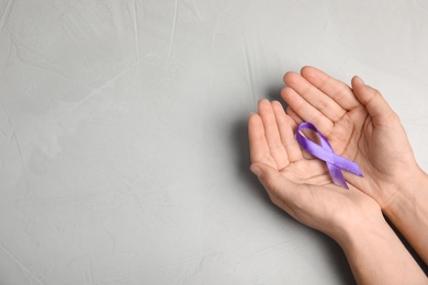 Photo of Woman holding purple ribbon on grey background, top view with space for text. Domestic violence awareness