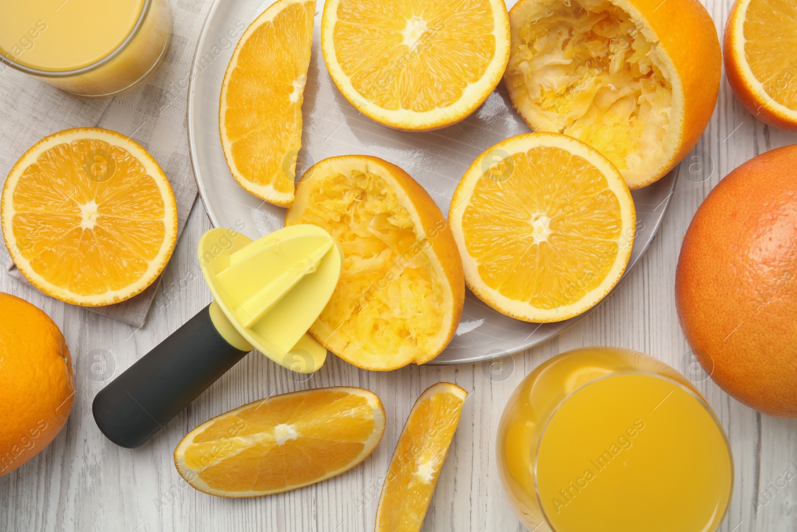 Photo of Fresh oranges, reamer and juice on white wooden table, flat lay