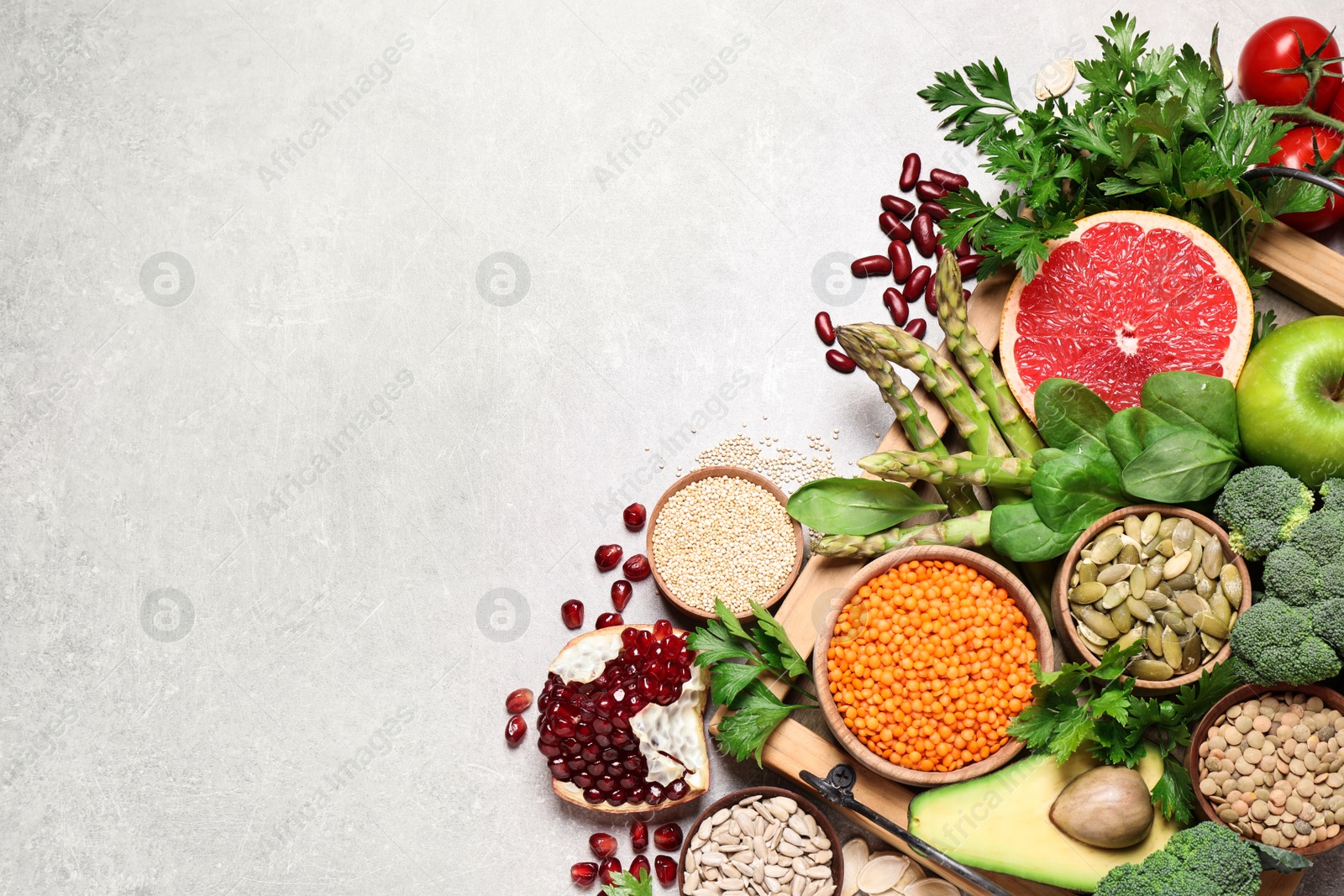 Photo of Fresh vegetables, fruits and seeds on grey table, flat lay. Space for text