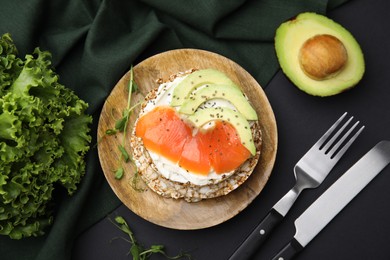 Photo of Crunchy buckwheat cakes served with cream cheese, salmon and avocado on black table, flat lay