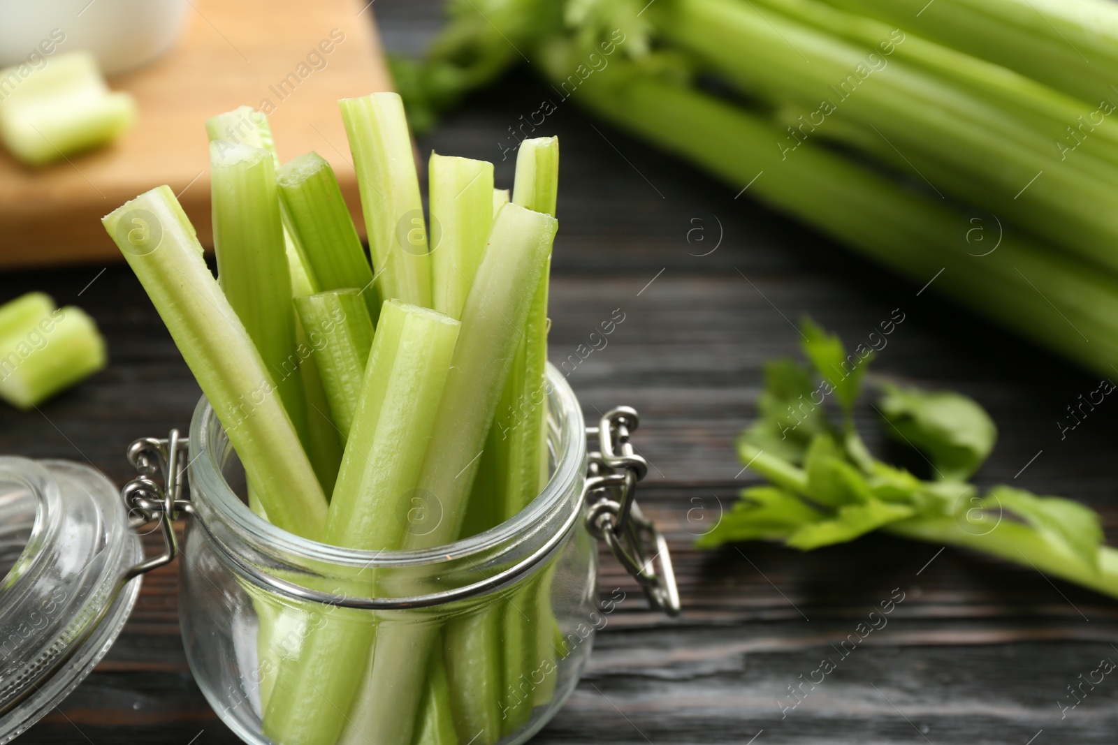 Photo of Celery sticks in jar on dark wooden table, closeup. Space for text
