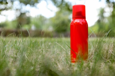 Bottle of insect repellent spray on grass. Space for text